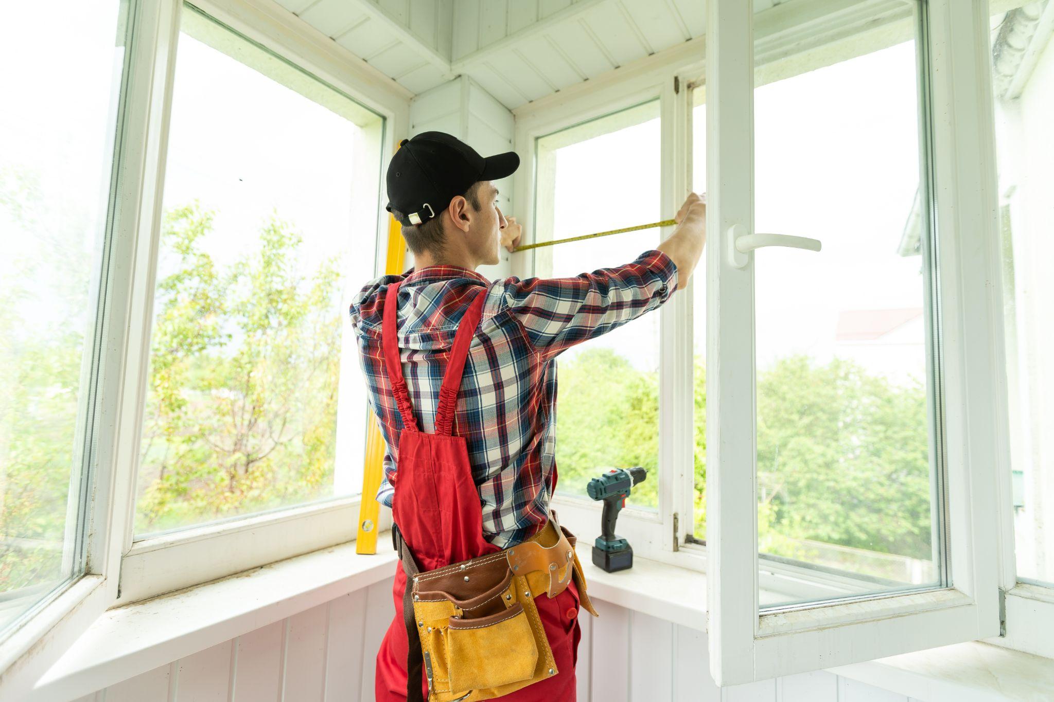 Man measuring window prior to installation of roller shutter outdoors.