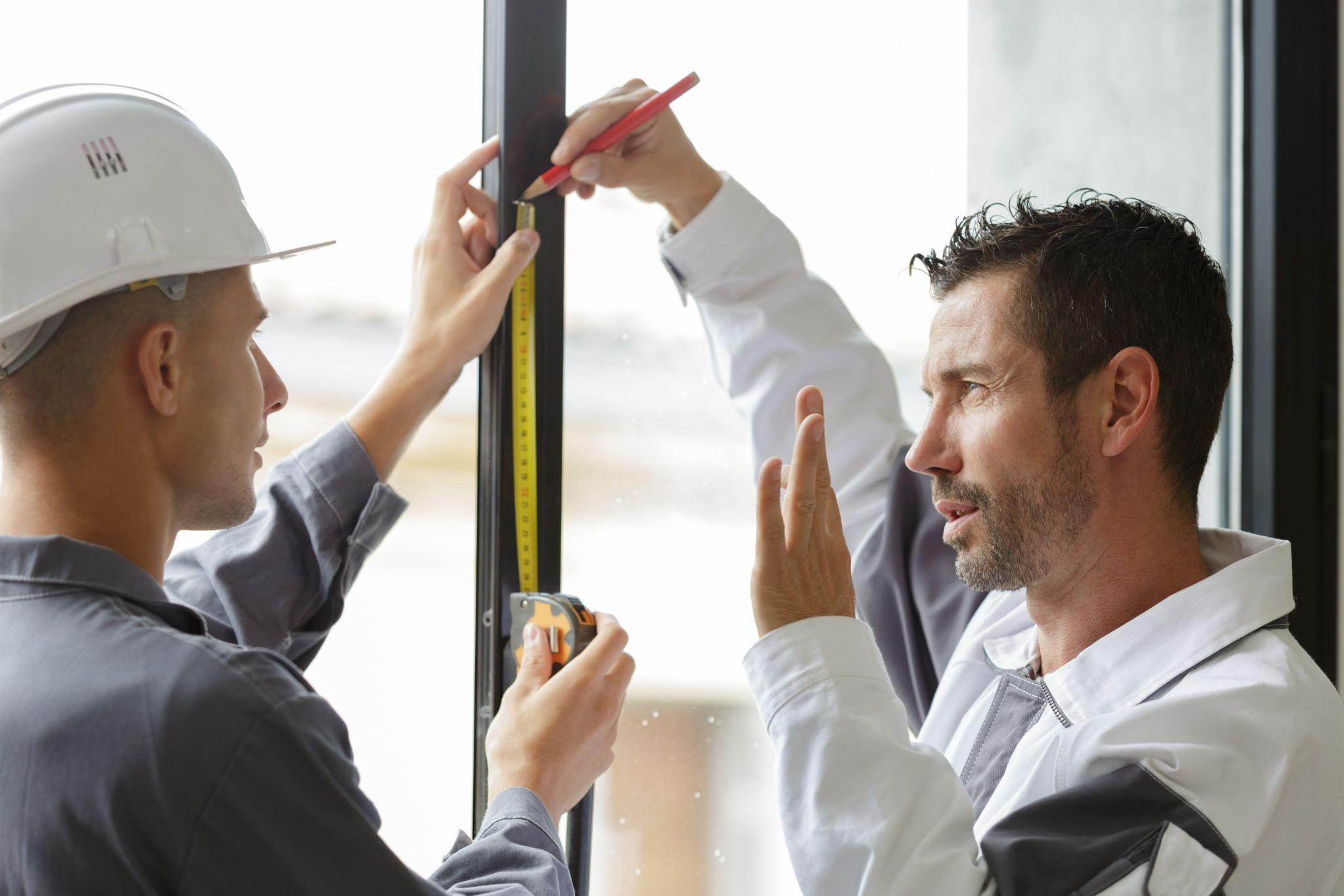 service men installing windows with measure tape